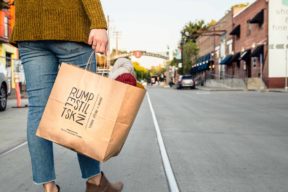 A person standing with a Rumpelstiltskin bag looking down R street